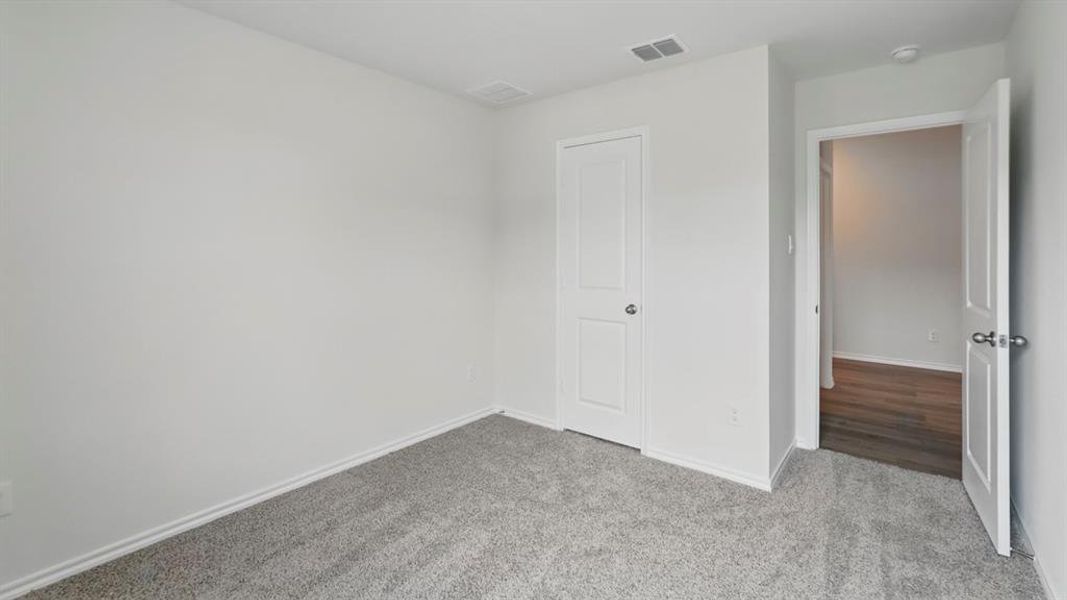 Interior room featuring light grey carpeting, white baseboards, and neutral wall paint