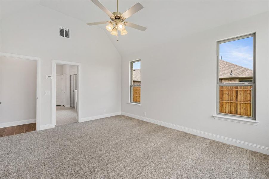 Unfurnished bedroom with carpet floors, multiple windows, high vaulted ceiling, and ceiling fan