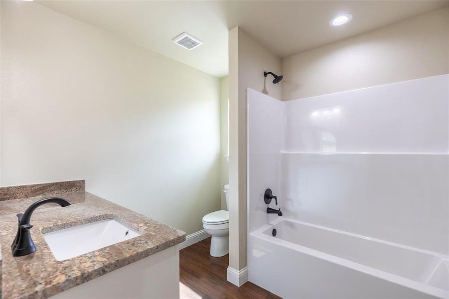 Bathroom featuring a white vanity with an undermount sink, a granite-finish countertop, and a matte black faucet