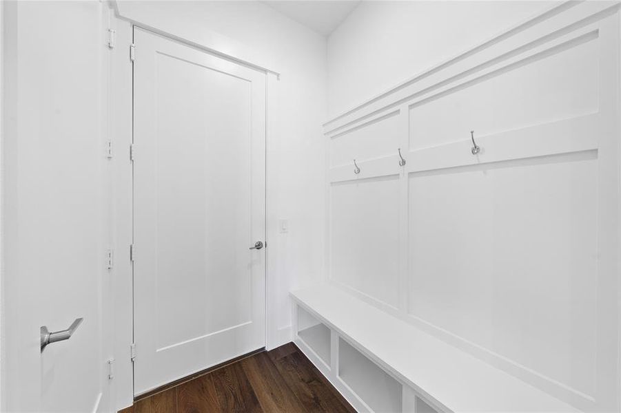 Entryway featuring a built-in bench with storage cubbies, decorative wainscoting, and integrated coat hooks