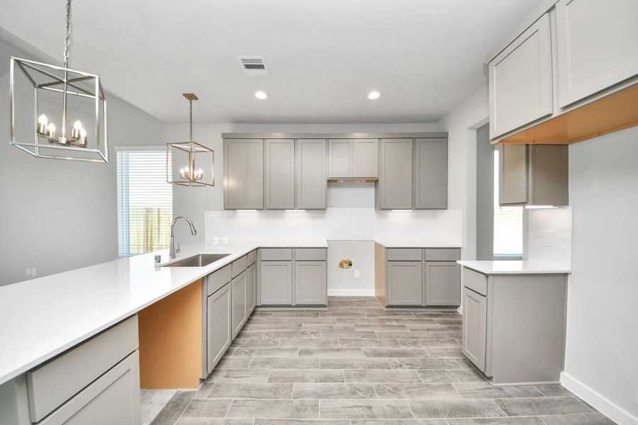 The kitchen is a culinary haven, featuring granite countertops, a tile backsplash, stainless steel appliances, 42” upper cabinets, and undercabinet lighting. Sample photo of completed home with similar floor plan. Actual colors and selections may vary. The kitchen is a culinary haven, featuring granite countertops, a tile backsplash, stainless steel appliances, 42” upper cabinets, and undercabinet lighting. Sample photo of completed home with similar floor plan. Actual colors and selections may vary.