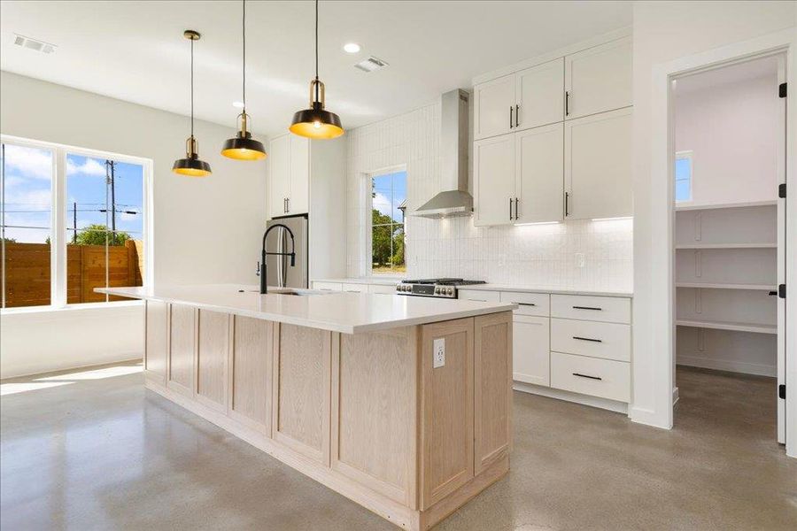 Kitchen with healthy amount of natural light, light brown cabinetry, finished concrete flooring, and recessed lighting