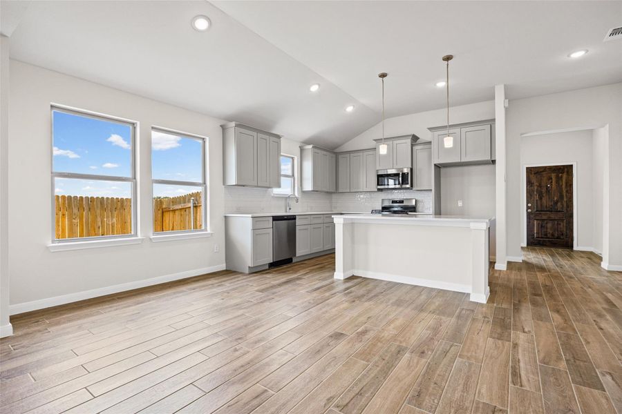 Gleaming wood-look tile floors and vaulted ceilings frame this open culinary space. Gleaming wood-look tile floors and vaulted ceilings frame this open culinary space.