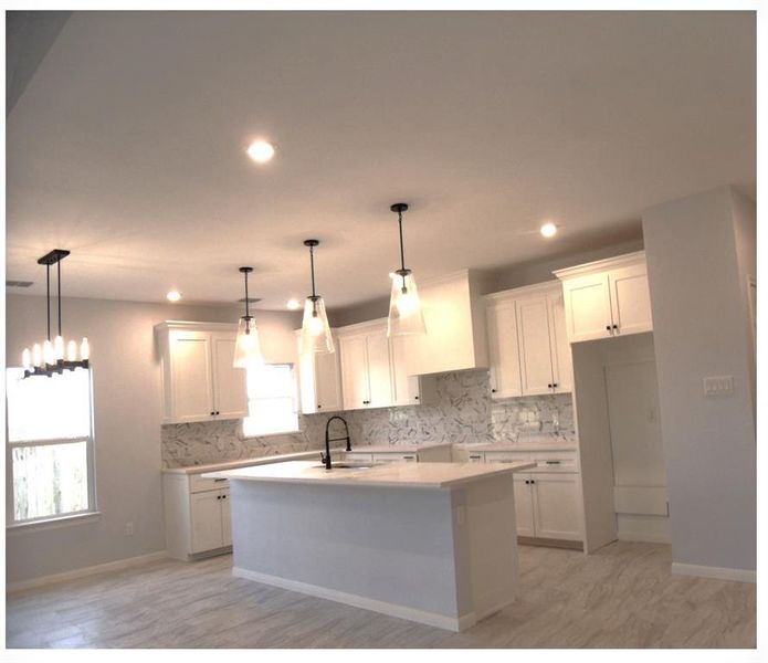 Kitchen with white cabinetry, a healthy amount of sunlight, and a kitchen island with sink