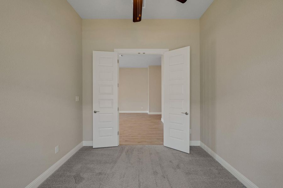 Carpeted spare room featuring baseboards and a ceiling fan