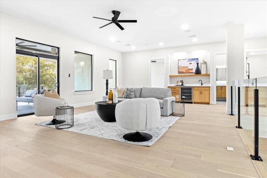 Living room with beverage cooler, light hardwood / wood-style floors, sink, and ceiling fan