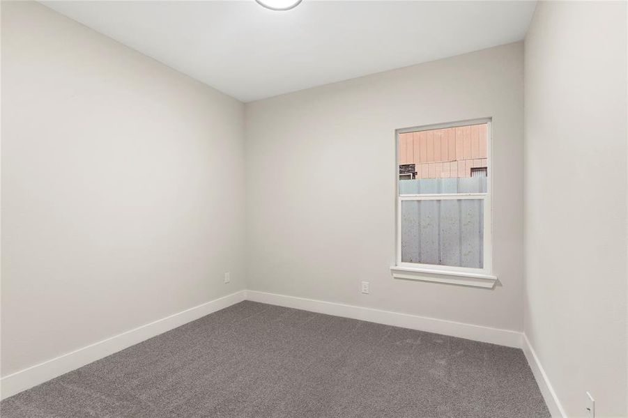 Spare room with dark carpet and baseboards