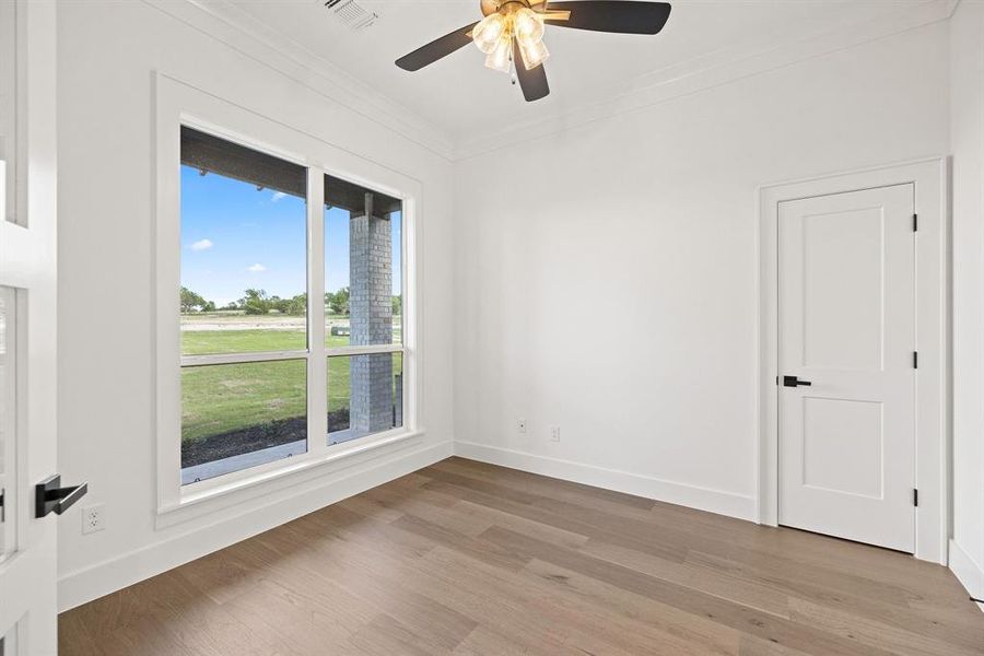 Unfurnished room with light wood finished floors, visible vents, a ceiling fan, crown molding, and baseboards
