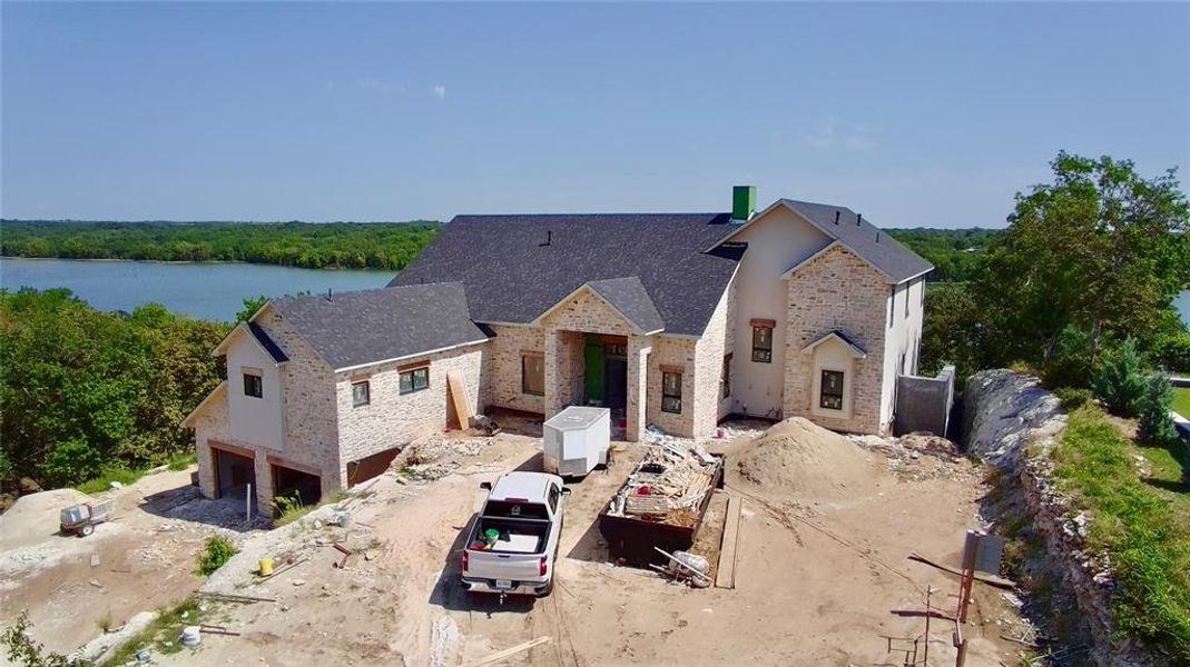View of front of property with an attached garage, roof with shingles, stone siding, and driveway View of front of property with an attached garage, roof with shingles, stone siding, and driveway