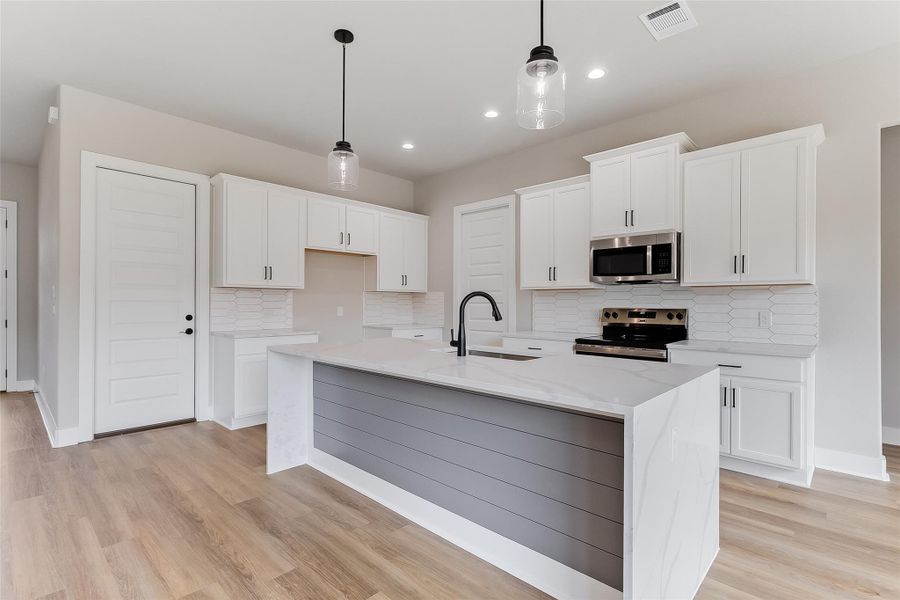 Modern kitchen featuring large center island with waterfall-style quartz countertops, large pantry, modern fixtures, and sleek cabinetry Modern kitchen featuring large center island with waterfall-style quartz countertops, large pantry, modern fixtures, and sleek cabinetry