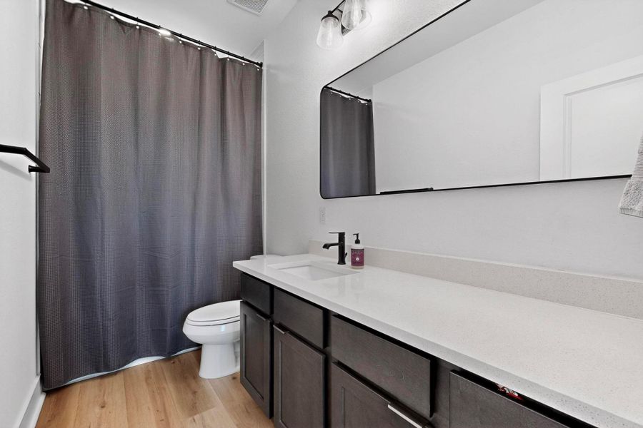 Bathroom with light wood-style floors, curtained shower, and vanity
