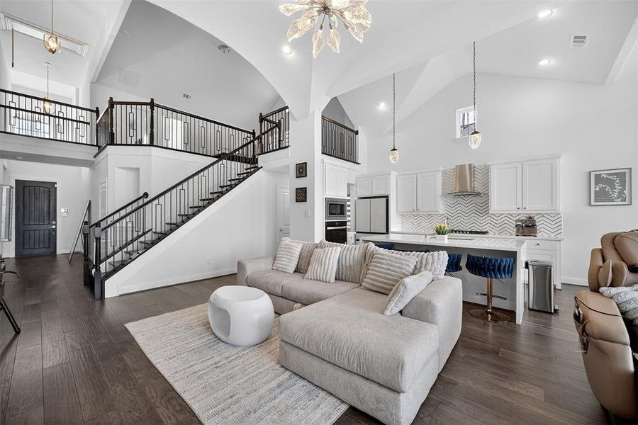Living room featuring a chandelier, high vaulted ceiling, dark wood-style floors, stairs, and recessed lighting Living room featuring a chandelier, high vaulted ceiling, dark wood-style floors, stairs, and recessed lighting