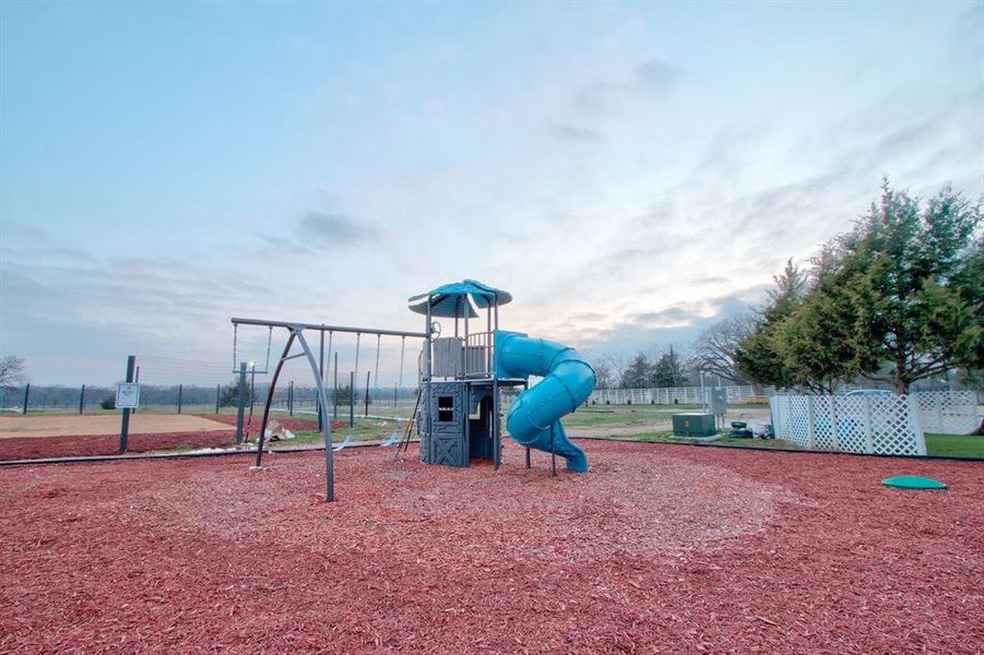 Outdoor playground with swing seat, covered slide and climbing fort.