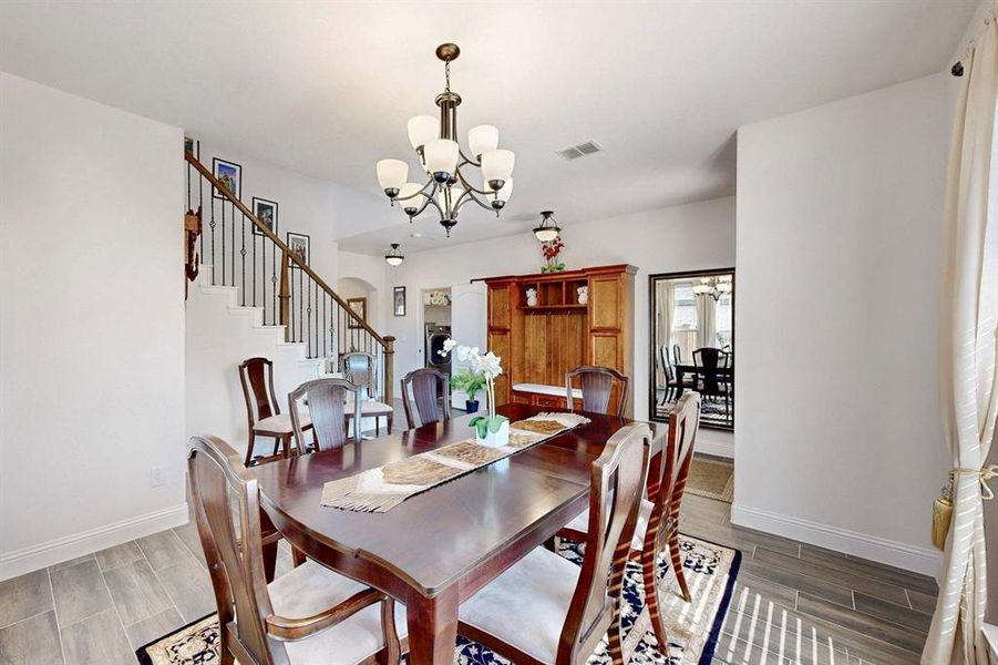 Dining area with wood finish floors, a chandelier, and stairs