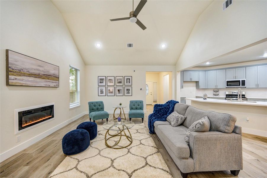 Spacious living room with high ceilings, modern fireplace, and seamless flow to the kitchen—perfect for entertaining.
