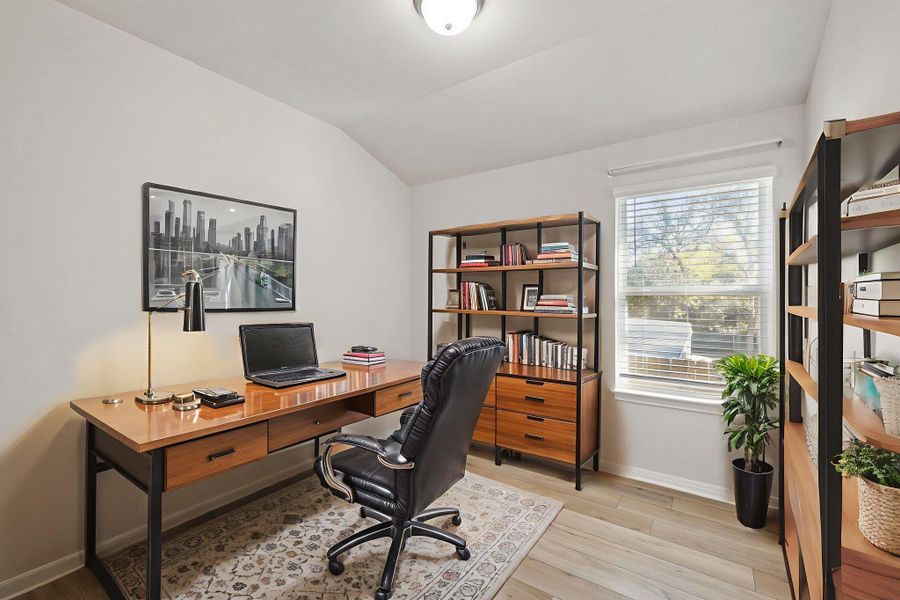 Office space with vaulted ceiling and light wood finished floors Office space with vaulted ceiling and light wood finished floors