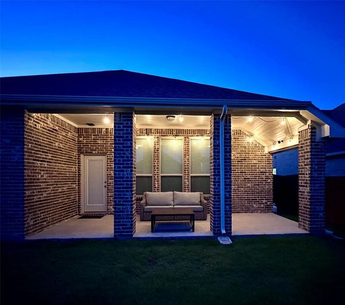 Patio terrace at twilight with an outdoor living space and a yard