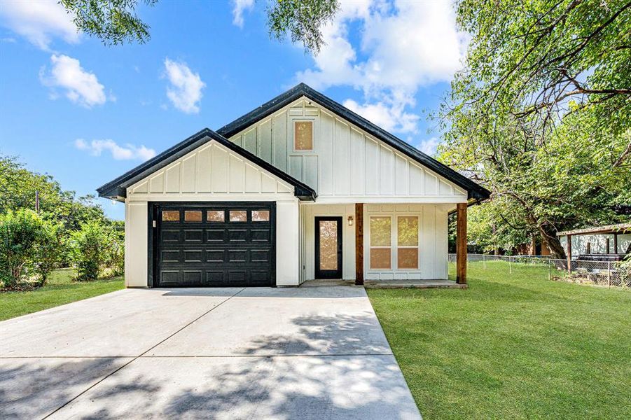 Modern farmhouse style home with board and batten siding, covered porch, concrete driveway, and an attached garage Modern farmhouse style home with board and batten siding, covered porch, concrete driveway, and an attached garage
