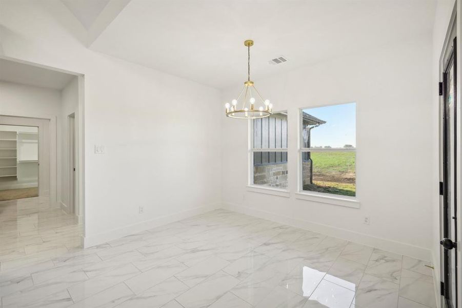 Unfurnished dining area with light marble finish flooring and a chandelier Unfurnished dining area with light marble finish flooring and a chandelier