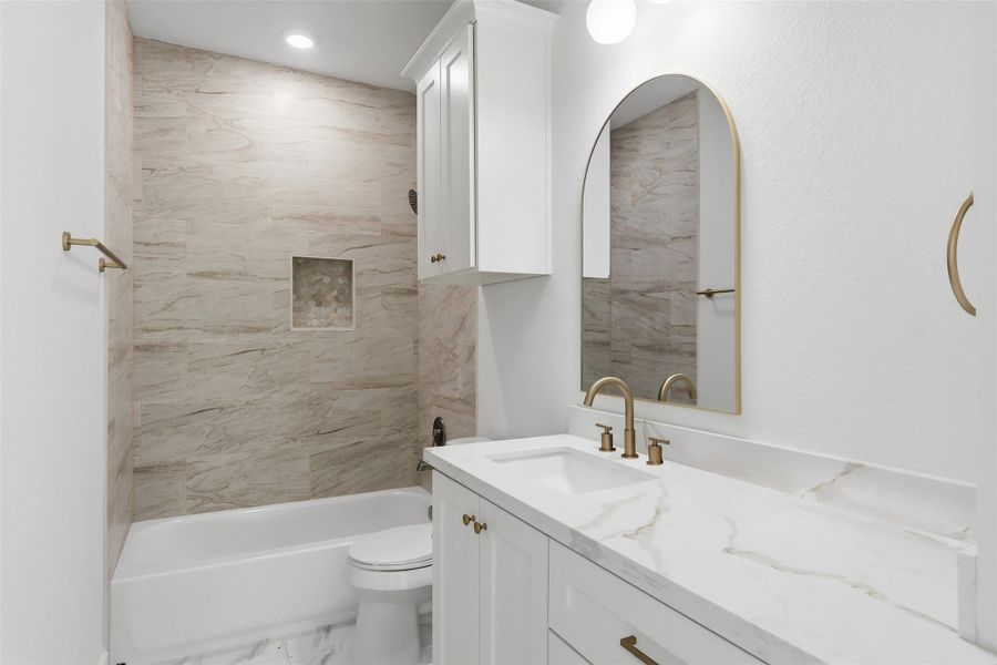 The secondary full bath features a shower-tub combo, quartz countertops, and custom cabinetry for additional storage.
