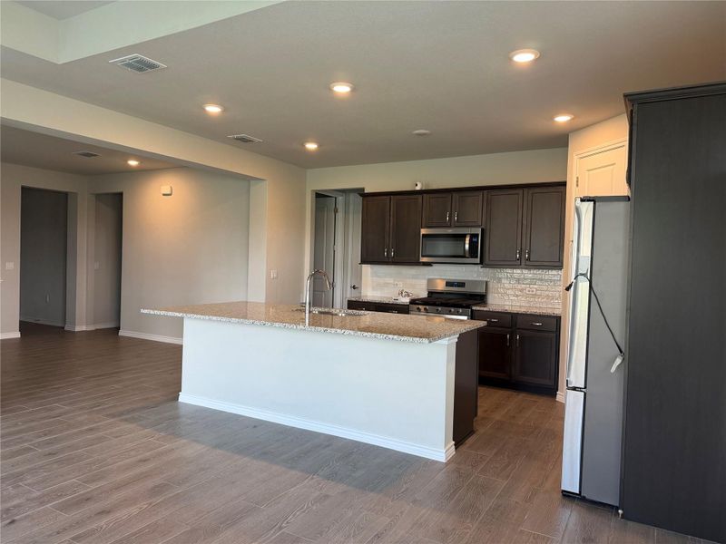 An open-concept kitchen with recessed lighting and wood-look tile flooring awaits culinary adventures.