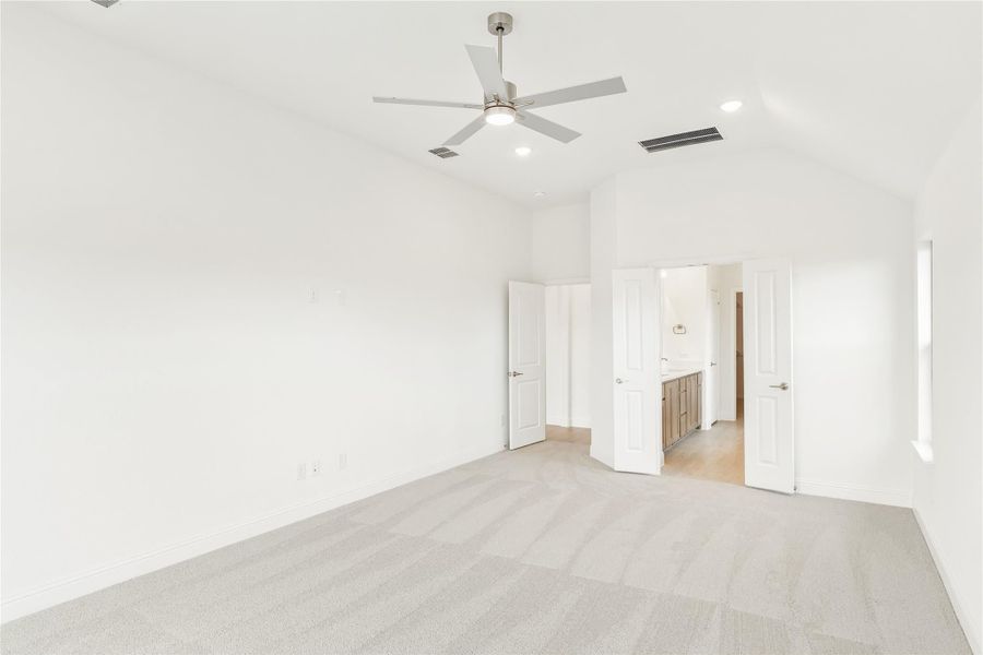 Empty bedroom with carpet, ceiling fan, and open door leading to ensuite bathroom Empty bedroom with carpet, ceiling fan, and open door leading to ensuite bathroom