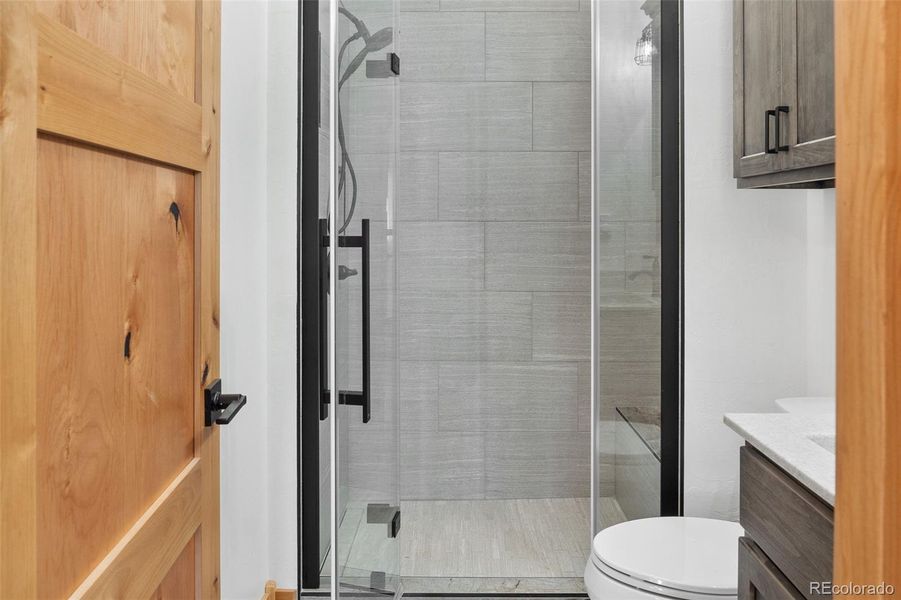 Upper level 3/4 bath -Custom tile, cabinets, onyx counter/sink and frameless glass shower door