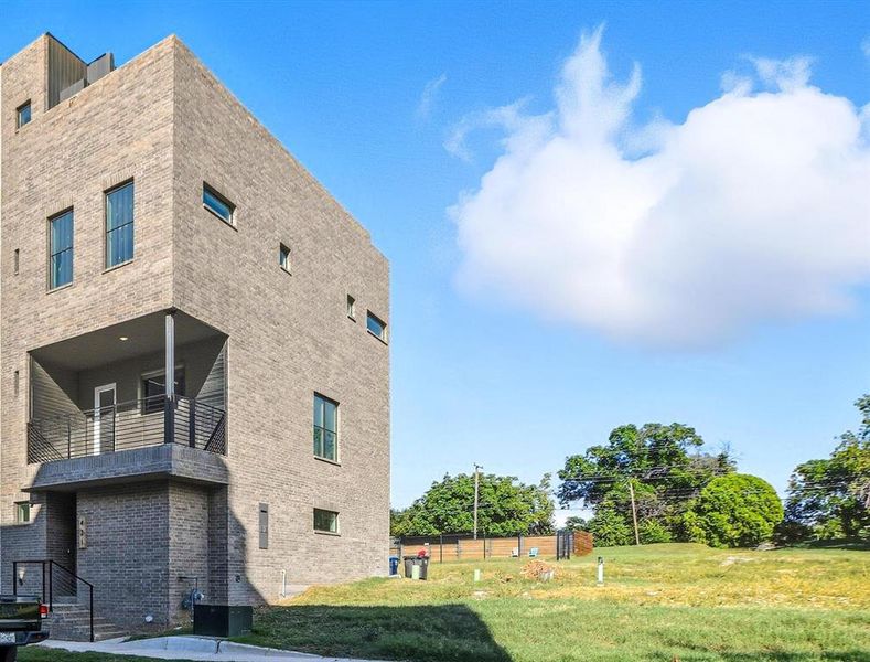 View of home's exterior featuring brick siding and a balcony View of home's exterior featuring brick siding and a balcony