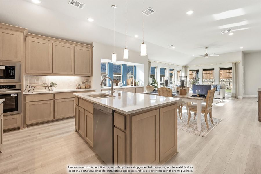 Open-concept kitchen with light wood cabinets, large island, and pendant lights, flowing into dining and living areas with hardwood floors Open-concept kitchen with light wood cabinets, large island, and pendant lights, flowing into dining and living areas with hardwood floors