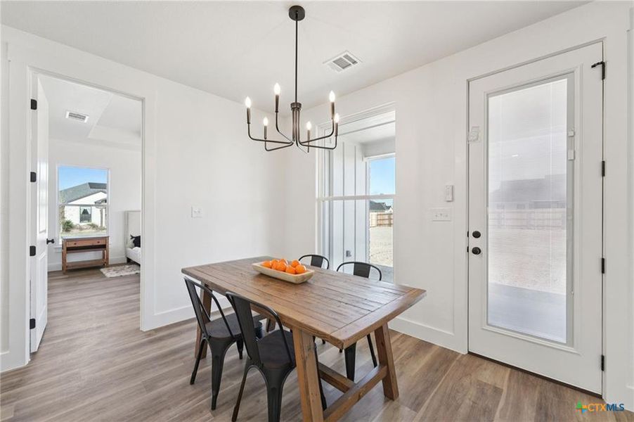 A well-lit dining area featuring a classic chandelier and light wood flooring. A well-lit dining area featuring a classic chandelier and light wood flooring.