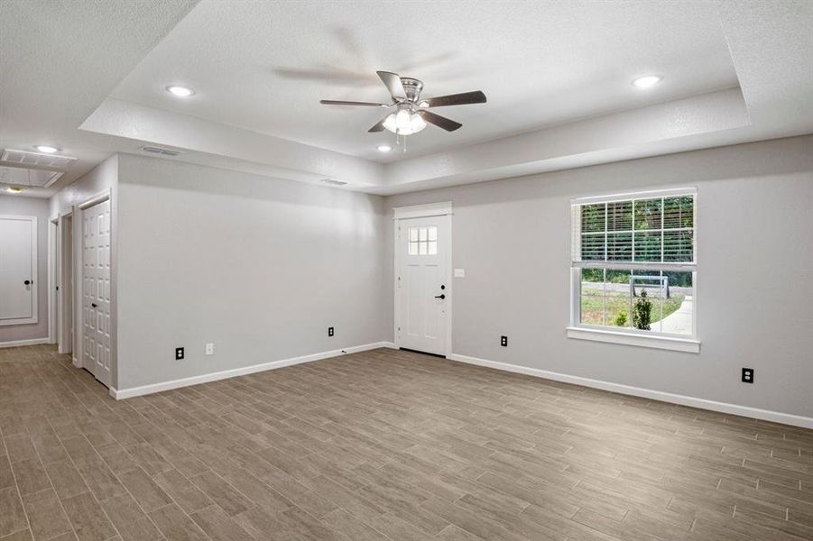 Unfurnished living room with a tray ceiling, healthy amount of natural light, and recessed lighting Unfurnished living room with a tray ceiling, healthy amount of natural light, and recessed lighting