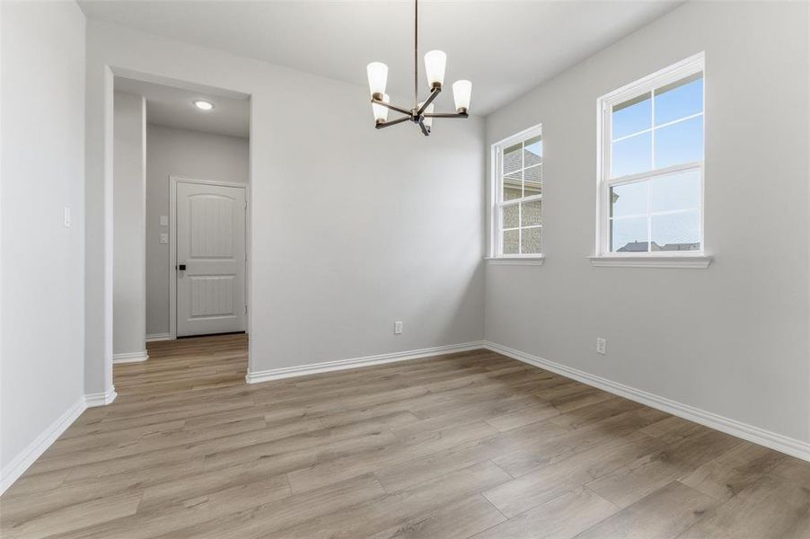 Empty room with hanging lights and light wood-style flooring