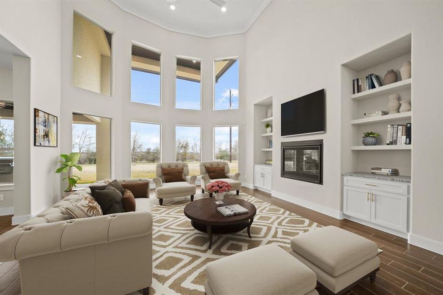 Virtually Staged: Walk through the foyer past the staircase and arrive at this incredible living room! Highlighting stunning floor to ceiling windows, a high ceiling with a ceiling fan, built-in shelves, and an absolutely gorgeous fireplace.