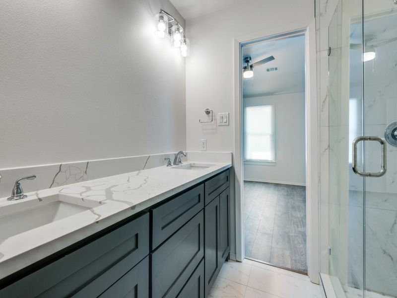 Bathroom with hardwood / wood-style flooring, ceiling fan, a shower with door, and dual bowl vanity