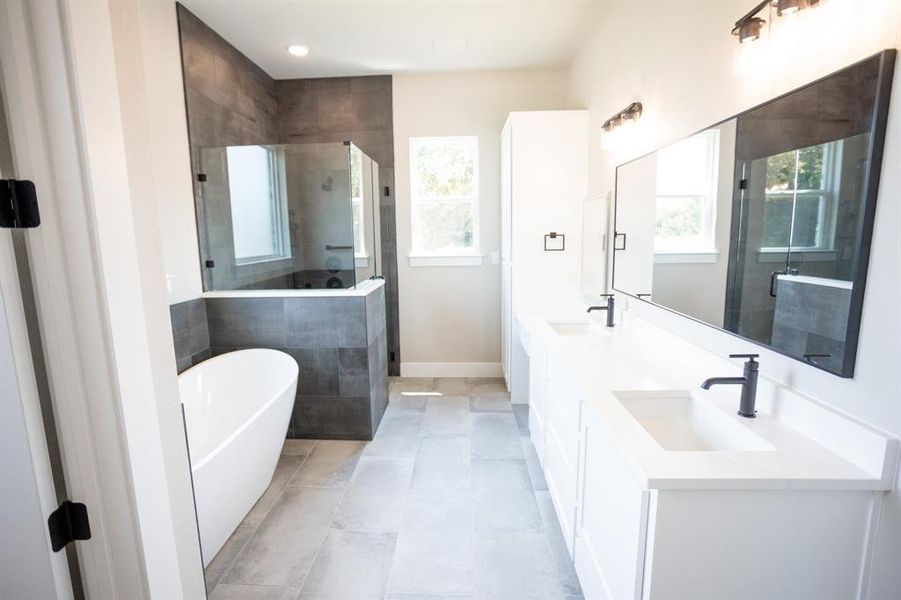Full bath featuring a stall shower, a freestanding tub, double vanity, and light tile patterned floors Full bath featuring a stall shower, a freestanding tub, double vanity, and light tile patterned floors