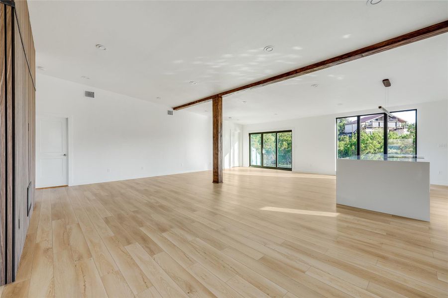 Unfurnished room with light wood-style flooring and beam ceiling Unfurnished room with light wood-style flooring and beam ceiling
