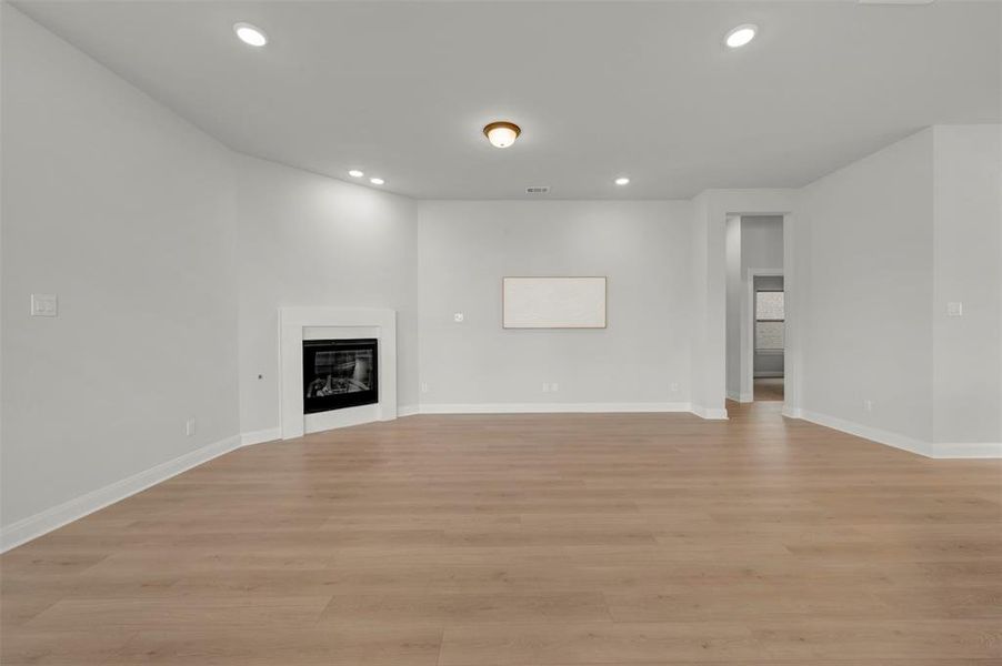 Unfurnished living room featuring a glass covered fireplace, light wood-style flooring, and recessed lighting