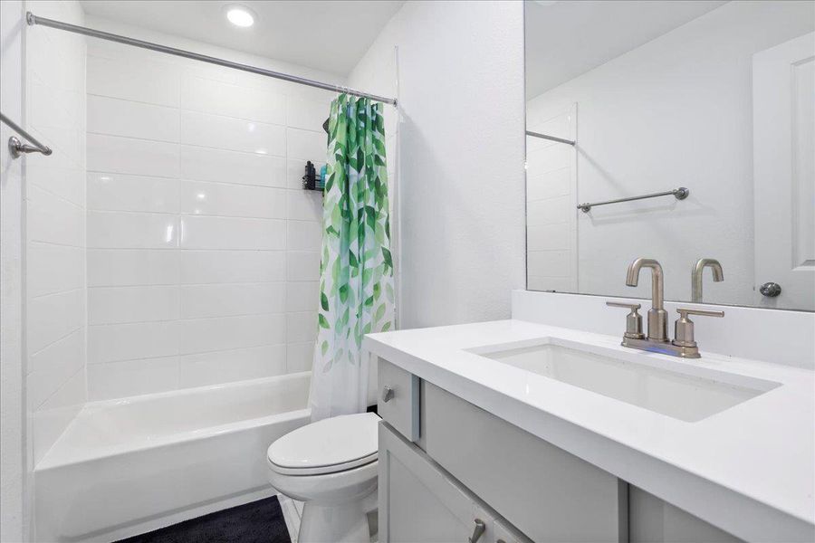 Bathroom featuring vanity and shower / bathtub combination with curtain