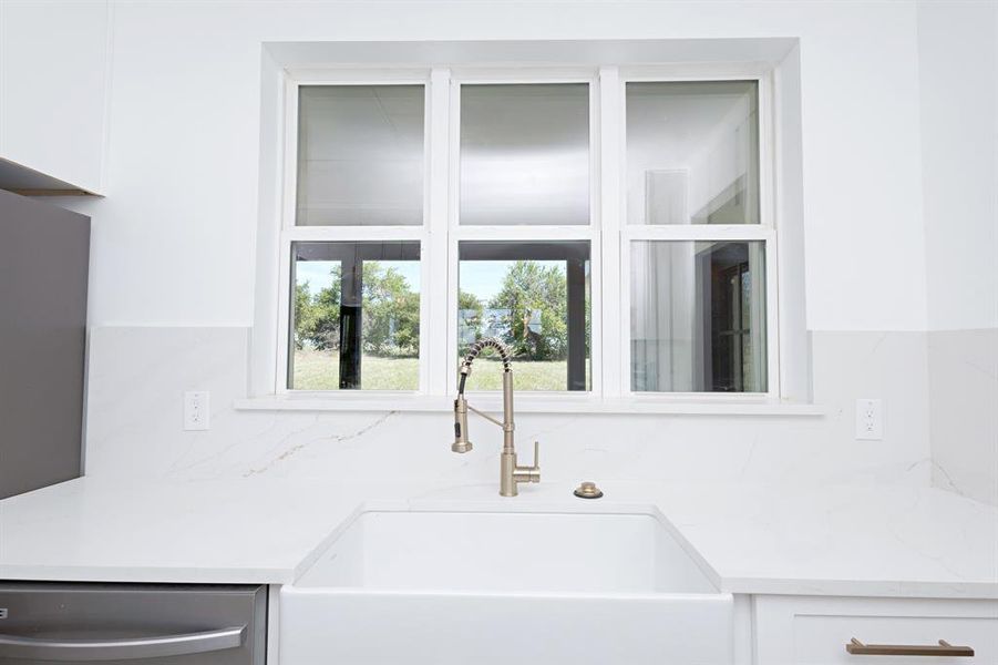 Kitchen featuring white cabinets, stainless steel dishwasher, and tasteful backsplash