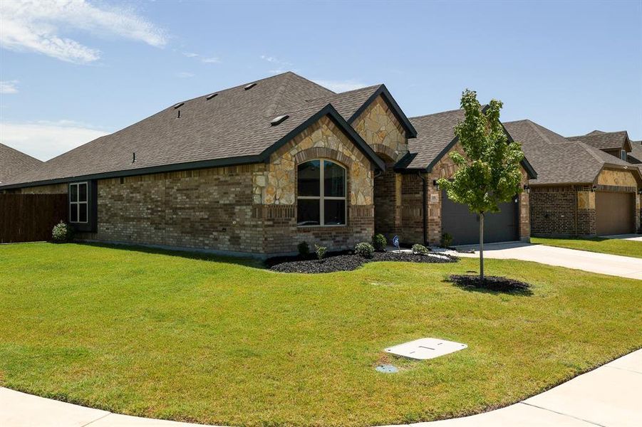 View of front of house with concrete driveway, brick siding, an attached garage, roof with shingles, and stone siding