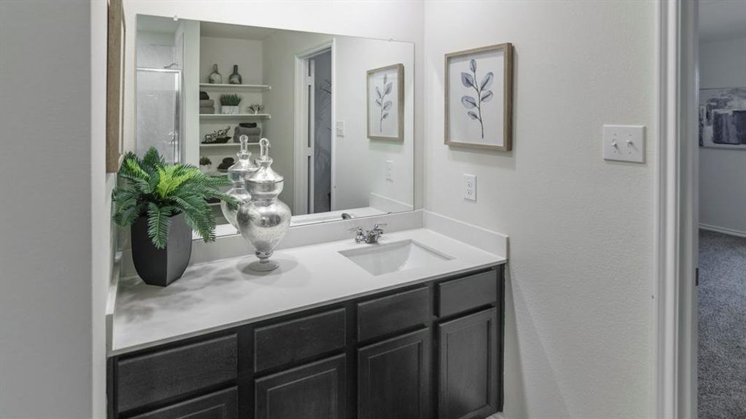 Bathroom vanity with an integrated sink, a large wall-mounted mirror, and dark wood-finish cabinetry Bathroom vanity with an integrated sink, a large wall-mounted mirror, and dark wood-finish cabinetry