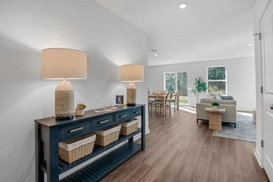 A room with a wood floor and a wood floor with a table and chairs and a lamp.
