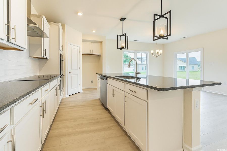 Kitchen featuring recessed lighting, a kitchen island with sink, tasteful backsplash, hanging light fixtures, and white cabinetry Kitchen featuring recessed lighting, a kitchen island with sink, tasteful backsplash, hanging light fixtures, and white cabinetry