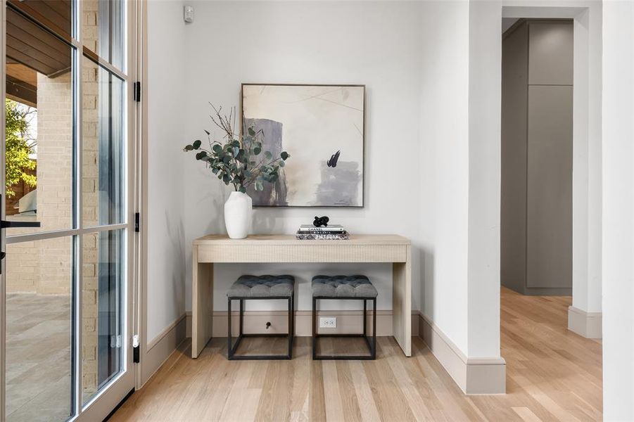 Hallway leading to utility room, mud room and garage with floor-to-ceiling windows ad doors.