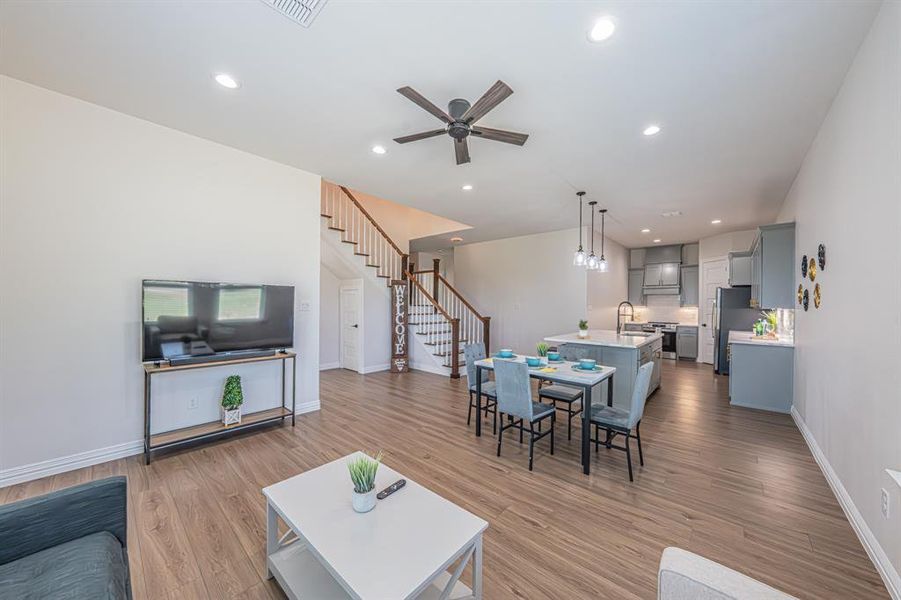 Living room featuring recessed lighting, light wood-type flooring, ceiling fan, and stairway Living room featuring recessed lighting, light wood-type flooring, ceiling fan, and stairway