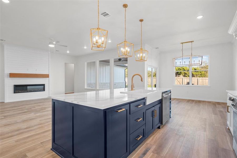 Kitchen with ceiling fan, blue cabinetry, pendant lighting, open floor plan, and recessed lighting