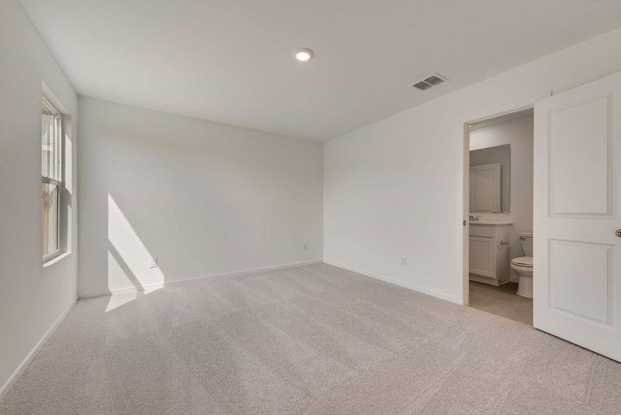 Unfurnished bedroom featuring light carpet, connected bathroom, and recessed lighting