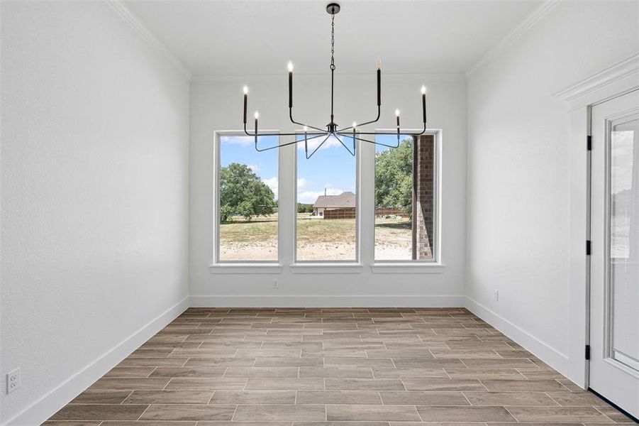 Unfurnished dining area with healthy amount of natural light, wood finish floors, ornamental molding, and a chandelier Unfurnished dining area with healthy amount of natural light, wood finish floors, ornamental molding, and a chandelier