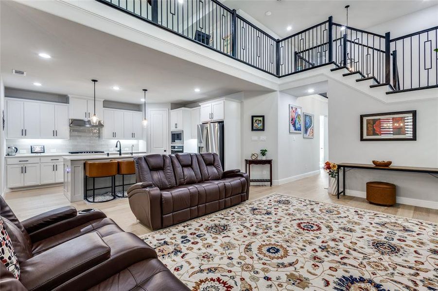 Living area featuring light wood finished floors, recessed lighting, and a high ceiling