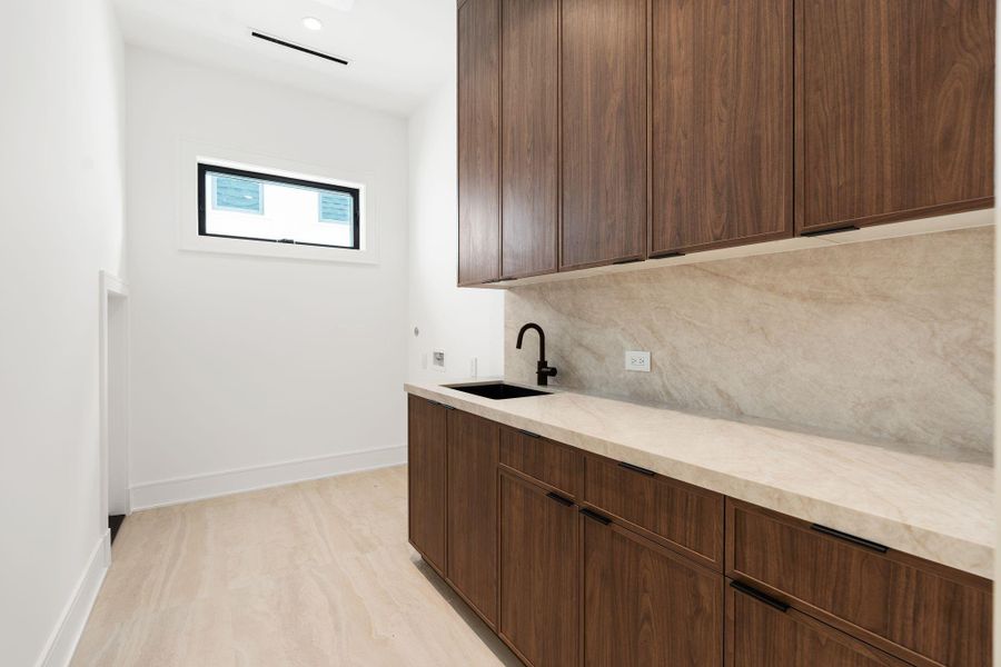 Utility room with abundance of cabinetry and sink.